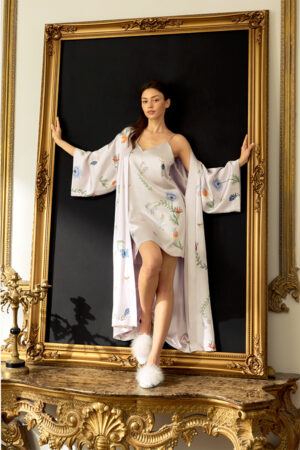 Woman steps through a grand frame in Alice Fantasy Forest Nightdress with flowing robe gliding for a calm morning.