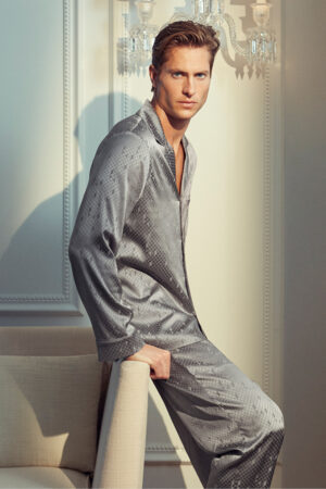 Seated view of MANITO Fragment Men's Pajama Set in silver silk with geometric jacquard pattern.