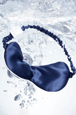 MANITO HA Silk Eye Mask in navy gently drifts through water, evoking a cool, hydrating sleep experience.