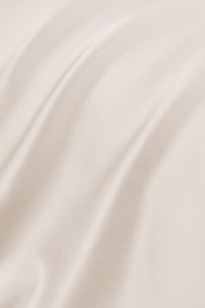 Close-up of the smooth and lustrous fabric of the MANITO Authentic Silk Flat Sheet in cream color.