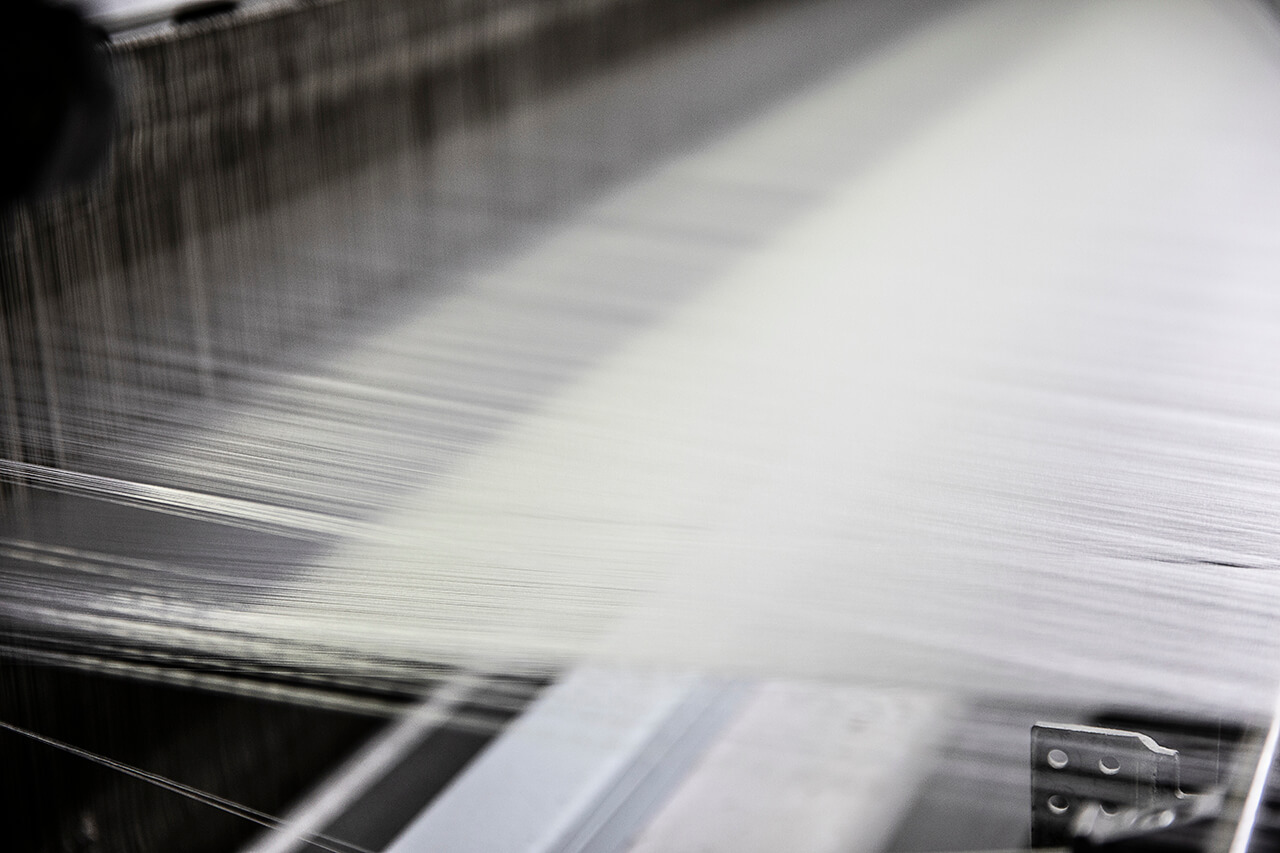 Close-up shot of shimmering silk threads on the loom, capturing the precision of luxury silk fabric production.