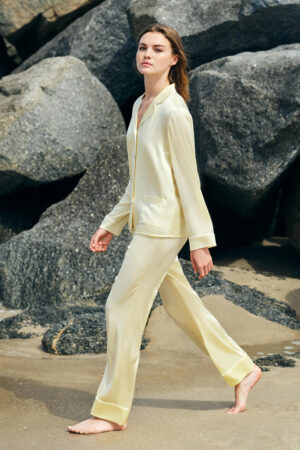 Woman walking along the beach in a New Authentic Women's Silk Pajama Set, with a tranquil ocean backdrop.
