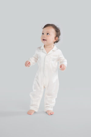Adorable baby in an white silk romper with button-up front.