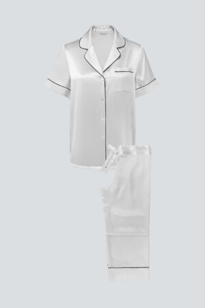 Flat lay of ivory MANITO Authentic Short Sleeve Pajama Set with black contrast piping and tailored look.