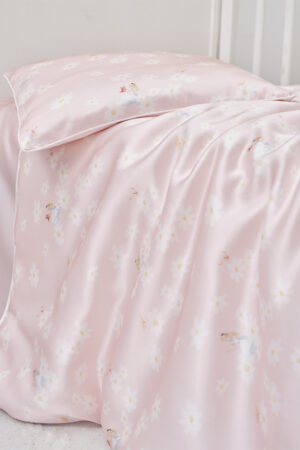 Close-up of Alice Daisy Children Bedding Sets, silky pink duvet and pillow with Alice and daisy details draped softly.
