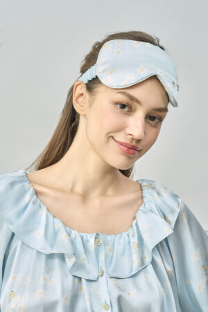 Model smiles softly in blue Alice Daisy Eye Mask with matching nightdress, capturing a moment of calm elegance.