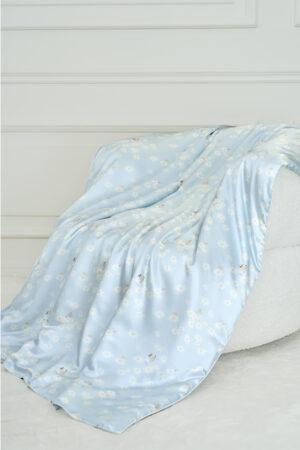 MANITO Alice Daisy Silk Blanket in blue, casually draped with Alice and daisy motifs, bringing soft comfort to your home.