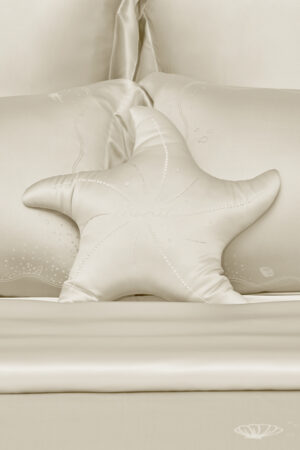 MANITO Ocean Starfish Throw Pillow on cream silk bedding set with subtle ocean-themed design.