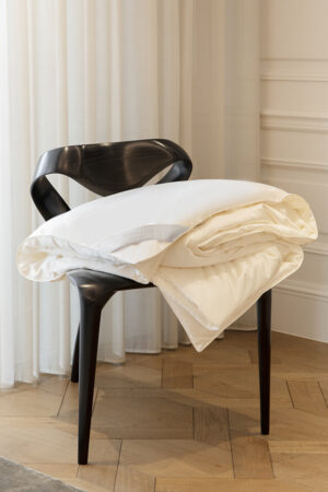 Premium MANITO silk duvet draped over a stylish modern chair, adding elegance to home interior.