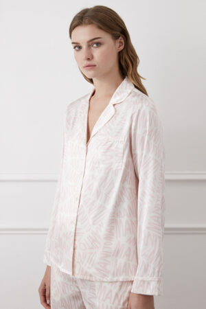 Woman in a sophisticated white Script Women's Pajama Set made of silk, featuring a subtle brand pattern.