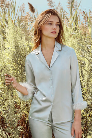 Young woman standing in a Diva Feather Trimmed Silk Pajama Set amidst a lush field.