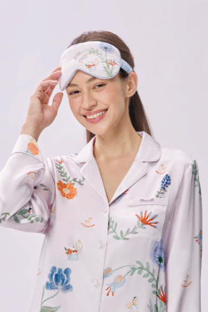 Woman lifts Alice Fantasy Forest Eye Mask with delicate Wonderland's prints, showing a soft and airy fit for everyday naps.